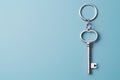 Silver key with space for message on keychain against a soft blue background representing the start of a new home era Royalty Free Stock Photo