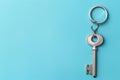 Silver key with space for message on keychain against a soft blue background representing the start of a new home era Royalty Free Stock Photo