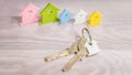 Silver Keychain laying on wooden Surface in front of miniature symbol of various coloured houses staying in line