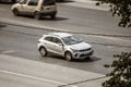 Silver Kia RIO car driving on a city road. Aerial side view of compact hatchback Kia KX Cross speeding on city highway