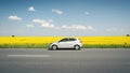 silver KIA Rio in parked front of rapeseed field Royalty Free Stock Photo