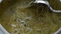 Silver ladle stirs bowl of chicken soup