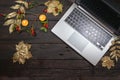 Silver laptop computer with gold painted autumn leaves, rose hips and candles on a dark rustic wooden table, seasonal business in Royalty Free Stock Photo