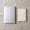 Silver laptop and cream-colored notebook placed side by side on a textured gray Royalty Free Stock Photo