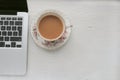 Silver laptop and milk tea in a china cup Royalty Free Stock Photo