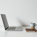 Silver laptop open on a white table, positioned on the left. To the right, a blue-gray Royalty Free Stock Photo