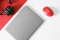 Silver laptop, red computer mouse and black wireless headphones on a red and white diagonal background. The concept of a modern Royalty Free Stock Photo