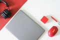 Silver laptop, red computer mouse, wireless headphones, pen and red box on red and white background. Concept of a modern workplace Royalty Free Stock Photo