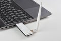 Silver laptop with USB modem plugged in with an antenna, on a white table Royalty Free Stock Photo