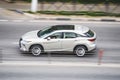 Silver Lexus RX Fourth generation AL20 japanese all-wheel drive SUV on city road. Aerial side view of car in motion. Woman talking