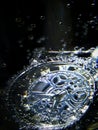 Silver mechanical watch in water and air bubbles