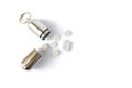 Silver medicine bottle with white pills next to it, isolated on white background. Portable key chain container for pills. Royalty Free Stock Photo