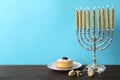 Silver menorah, dreidels with He, Pe, Nun, Gimel letters and sufganiyah on wooden table, space for text. Hanukkah symbols Royalty Free Stock Photo