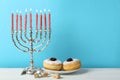 Silver menorah, dreidels with He, Pe, Nun, Gimel letters and sufganiyot on white table, space for text. Hanukkah symbols Royalty Free Stock Photo