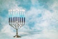 A silver menorah for the Jewish holiday Hanukkah with burning glowing eight candles