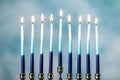 A silver menorah for the Jewish holiday Hanukkah with burning glowing eight candles