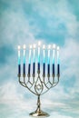 A silver menorah for the Jewish holiday Hanukkah with burning glowing eight candles