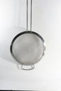 Silver mesh patterned strainer hanging from the wall