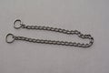 Silver metal chain with two rings on a gray background. Tugging