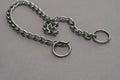 Silver metal chain with two rings on a gray background. Tugging