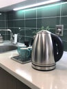 Silver metal electric kettle for boiling water and making tea on a table in the kitchen interior. Royalty Free Stock Photo