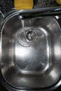 Silver metal kitchen sink close up shot with running tap water near the drain top view Royalty Free Stock Photo