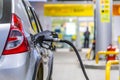 Silver metallic color car refueling on night gas station - close-up with selective focus and blurry man silhouette in Royalty Free Stock Photo