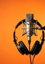 Silver microphone black headphones orange background Royalty Free Stock Photo