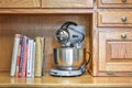 Mixmaster blender with cookbooks on shelf of oak sideboard