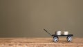 Silver money coin delivery on black toy wagon on wooden table