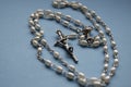 Silver necklace rosary on blue background