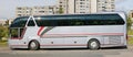 A silver Neoplan N516SHD bus is parked at the side of the road