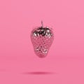 Silver painted strawberry floating on pink background