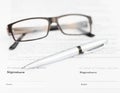 Silver pen and eyeglasses on signature page Royalty Free Stock Photo