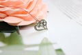 Silver pendant in the form of a heart on the background of a blossoming rose Royalty Free Stock Photo