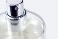Silver perfume spray cap and transparent glass bottle on light background close up with copy space. Royalty Free Stock Photo