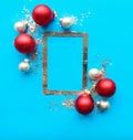 Silver photo frame and red Christmas baubles on bright blue background. Royalty Free Stock Photo