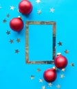 Silver photo frame and red Christmas baubles with stars on bright blue background. Royalty Free Stock Photo