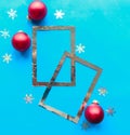 Silver photo frames and red Christmas baubles with stars on bright blue background. Royalty Free Stock Photo