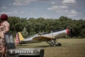 Silver plane with open cockpit with pilot on taxiway