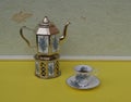 English teacup, saucer, silver-plated teapot on a silver stove, with floral decor