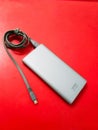 Silver power bank charger with grey cable data on red solid background Royalty Free Stock Photo