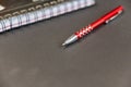 Silver-red pen and notepad against a black background. Ballpoint pen with a pattern of red squares Royalty Free Stock Photo