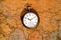 Silver retro pocket watch lying on a paper old world map. Antique gray round clock with a dial and golden hands on a Royalty Free Stock Photo