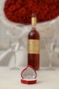 Silver ring in a box in the shape of a heart on the background of a bottle of wine, glasses and a bouquet of roses Royalty Free Stock Photo