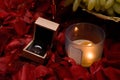 Silver ring with a burning candle in the midst of rose petals Royalty Free Stock Photo