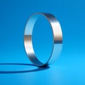 Silver ring casting a shadow on a blue surface creating a simple and elegant jewelry display shot Royalty Free Stock Photo