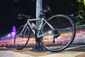 A silver road bike leaning onto a lamp pole on a side walk