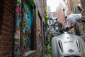 Silver scooter parked in empty brick alley with graffiti on the walls