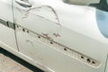 Silver scratched car with damaged door paint in crash accident or parking lot and dented damage of metal body from collision